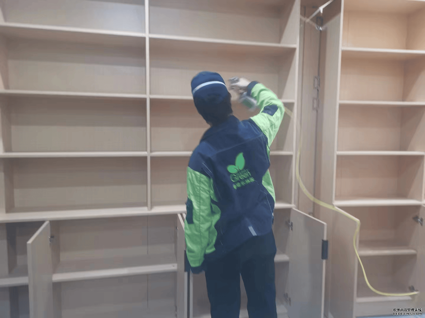 地下室施工时，施工人员相互配合，对大型储物架进行全面除醛作业，一人负责在高处进行喷涂，另一人在下方协助移动梯子和传递工具，确保储物架的每一层都能得到有效治理。